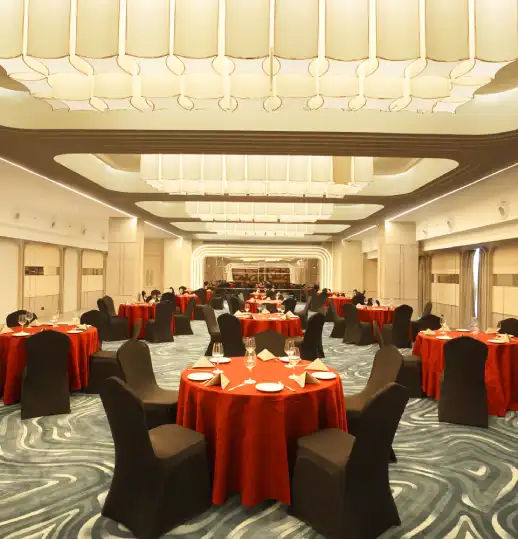Grand Chamber Hall – Ideal Venue for Banquets, Receptions, and Corporate Events Spacious banquet hall with elegant round tables, red covers, and ambient lighting