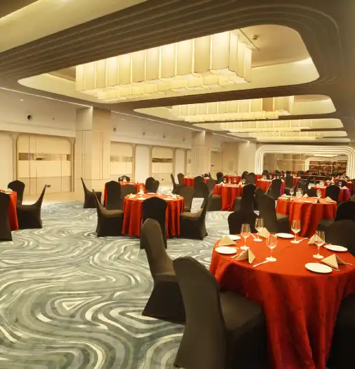 Grand Chamber Hall – Ideal Venue for Banquets, Receptions, and Corporate Events Spacious banquet hall with elegant round tables, red covers, and ambient lighting