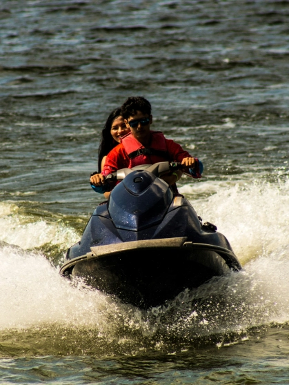 Three people stand on a beach at dusk, with narrow lighting creating.