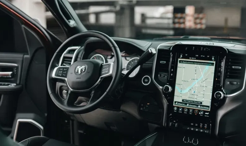 An overview of inside a car with the steering wheel, dashboard and screen in view