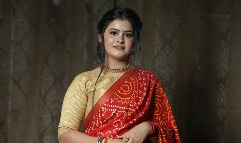 A portrait of a woman wearing a red bandhani saree