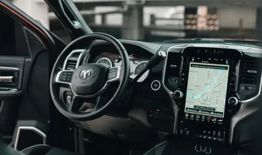 An overview of inside a car with the steering wheel, dashboard and screen in view