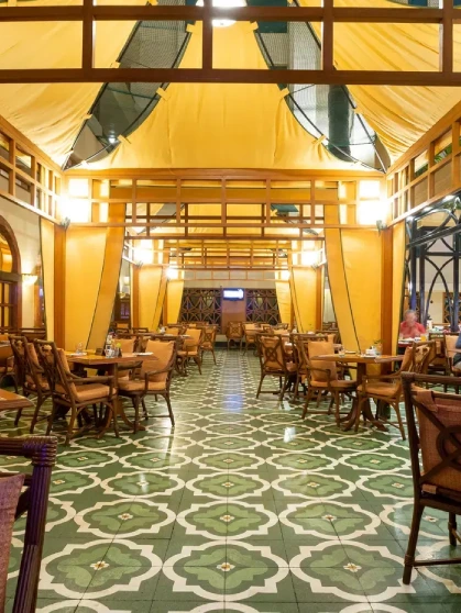 blue chairs and wooden table placed on a marbled floor with merlin's 99 signboard glowing in pink in the background