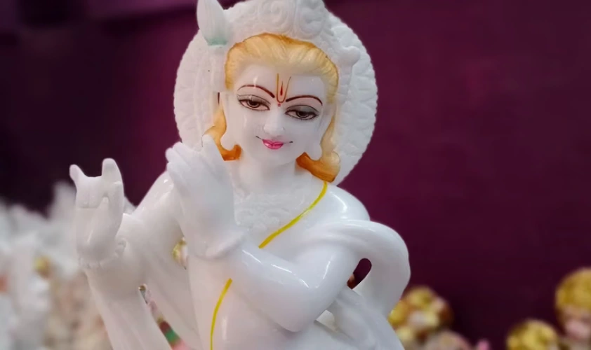 A white idol of Lord Krishna with golden carvings