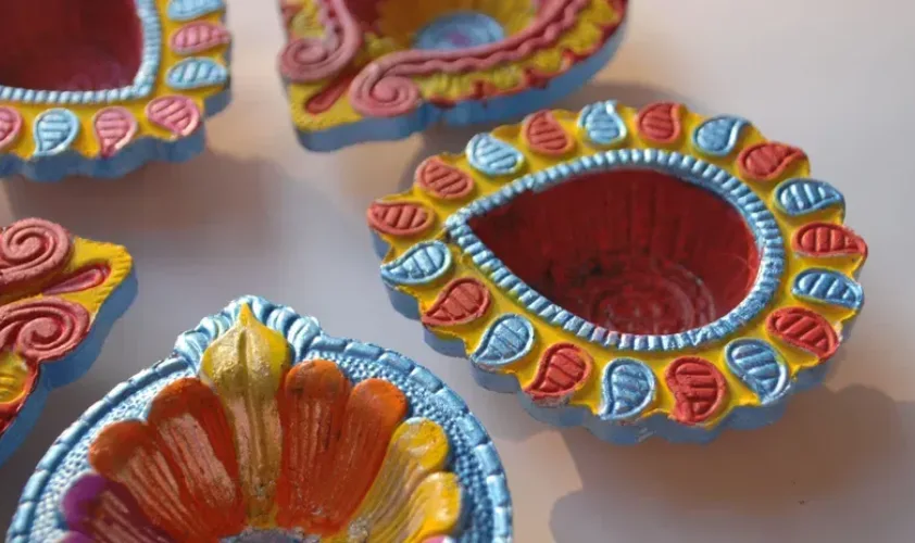 Five multi-colored diyas placed together
