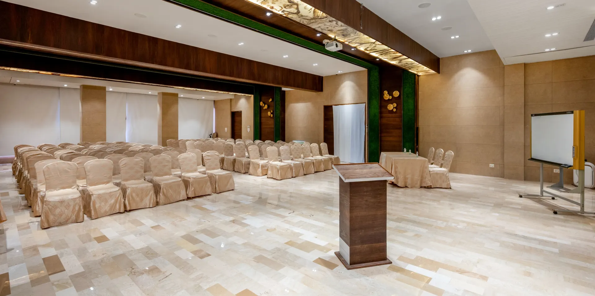 Book Banquet Hall in Panchgani – Orchid Hotel Conference & Wedding Venue Banquet hall with theatre-style seating, podium, and projector at Orchid Hotel Panchgani for conferences and weddings