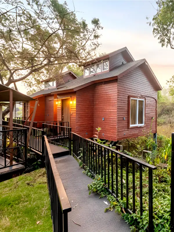 Wooden cottage suite exterior with walkway and lush greenery at sunset, Orchid Hotel Panchgani near Table Land