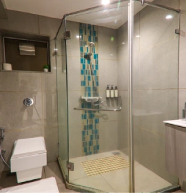 Dew Drop Room glass shower enclosure with teal mosaic tiles at hotel in Panchgani