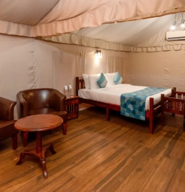Forest Tent Bedroom with Queen Bed and Wooden Floor - Panchgani Forest Tent interior with queen bed, wooden flooring, leather sofa and warm ambient lighting in Panchgani