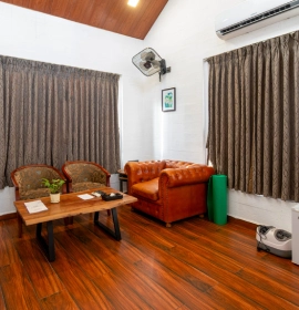 Tree House Suite living area with leather sofa and wooden flooring at Orchid Hotel Panchgani