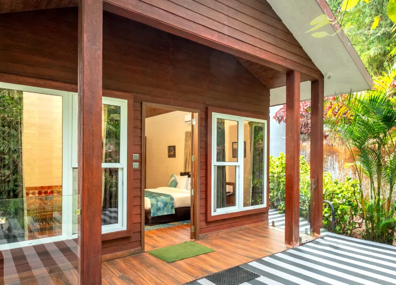 Exterior porch entrance of 350 sqft Wooden Cottage Suite surrounded by tropical garden at Orchid Hotel Panchgani