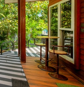 Private wooden balcony with bar stools and lush green garden view at Wooden Cottage Suite Orchid Hotel Panchgani