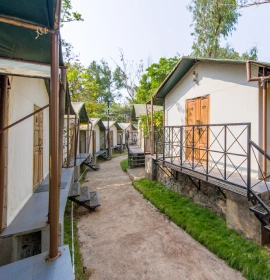 Forest Tent Eco Luxury Accommodation Exterior - Resort Panchgani Forest Tent eco luxury accommodation exterior row with pathway and wooden doors at resort in Panchgani