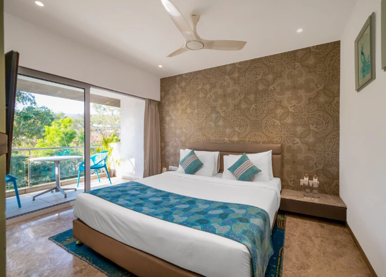 Strawberry Club Room 350 sqft with king bed, teal decor, ornate textured wall, ceiling fan and private balcony nature view at Orchid Hotel Panchgani