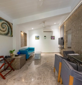 Strawberry Club Room spacious living area with blue sofa, marble flooring, ceiling fan and AC at Orchid Hotel Panchgani