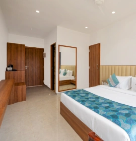 Wooden Tree House bedroom with king bed, teal runner, full-length mirror and wooden wardrobe in Panchgani